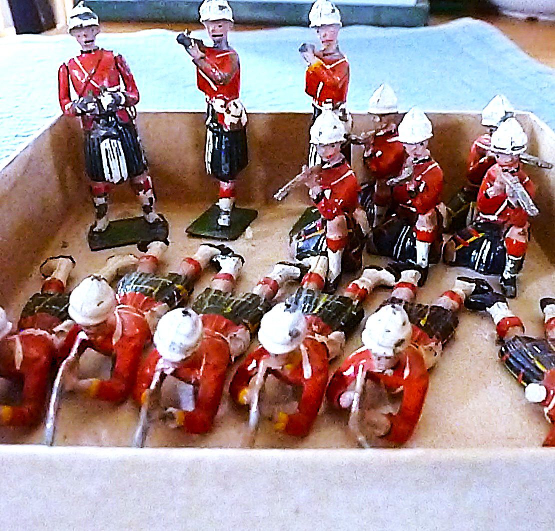 Vintage toy soldiers and motorcyclists in red uniforms arranged in a box.
