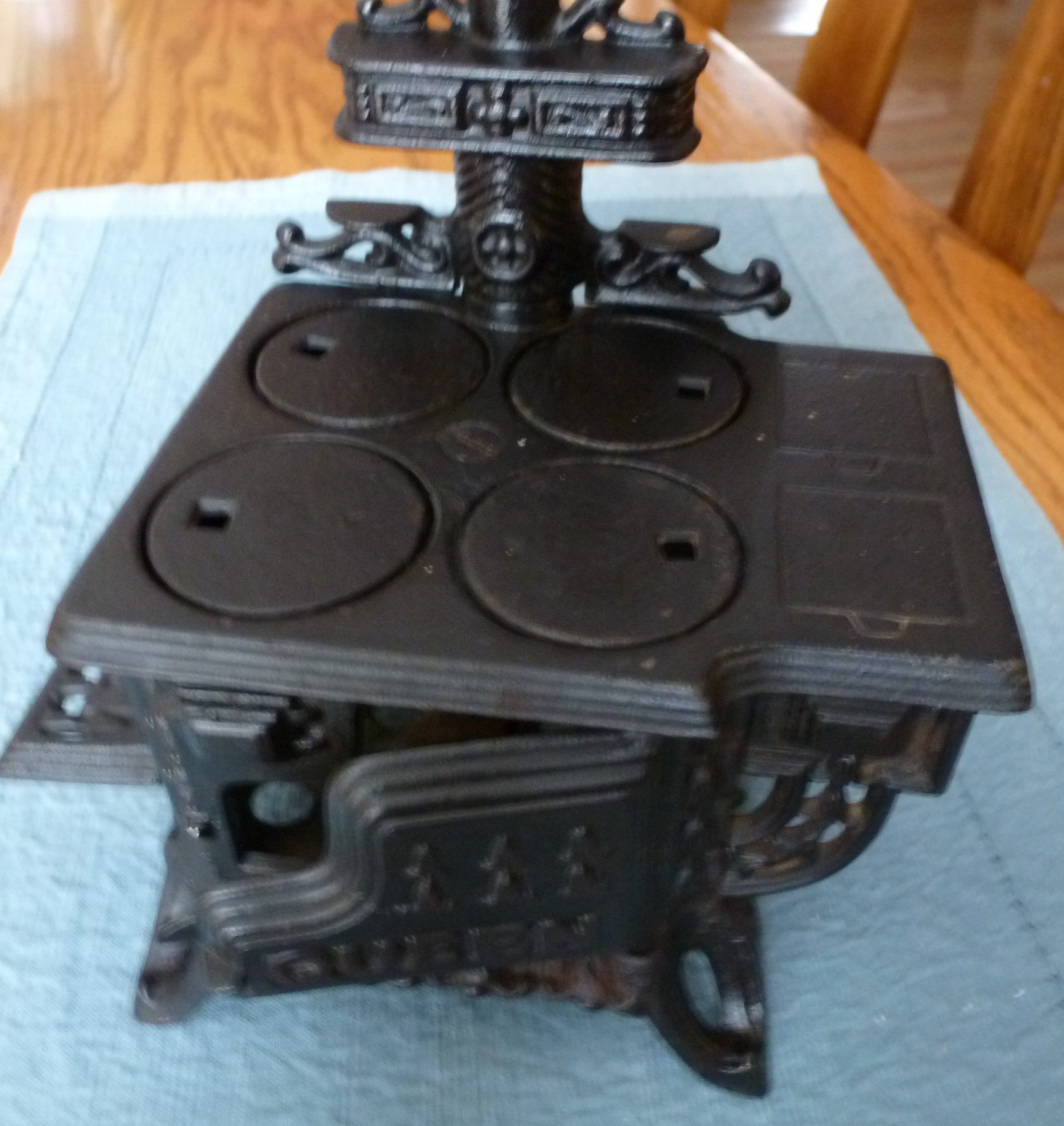 Antique cast iron stove with four circular burners and ornate legs.