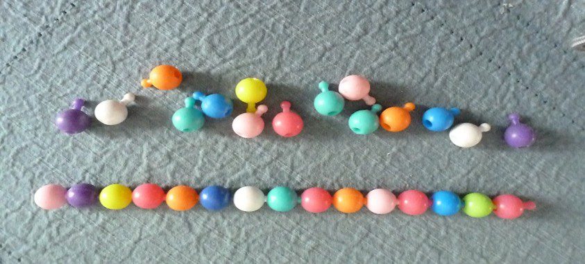 Colorful round beads strung in different patterns on a textured surface.