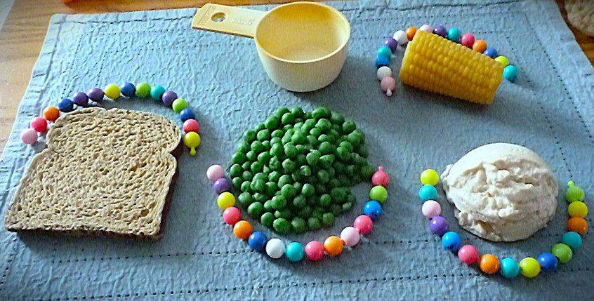 A playful arrangement of green peas and colorful beads on a blue cloth.