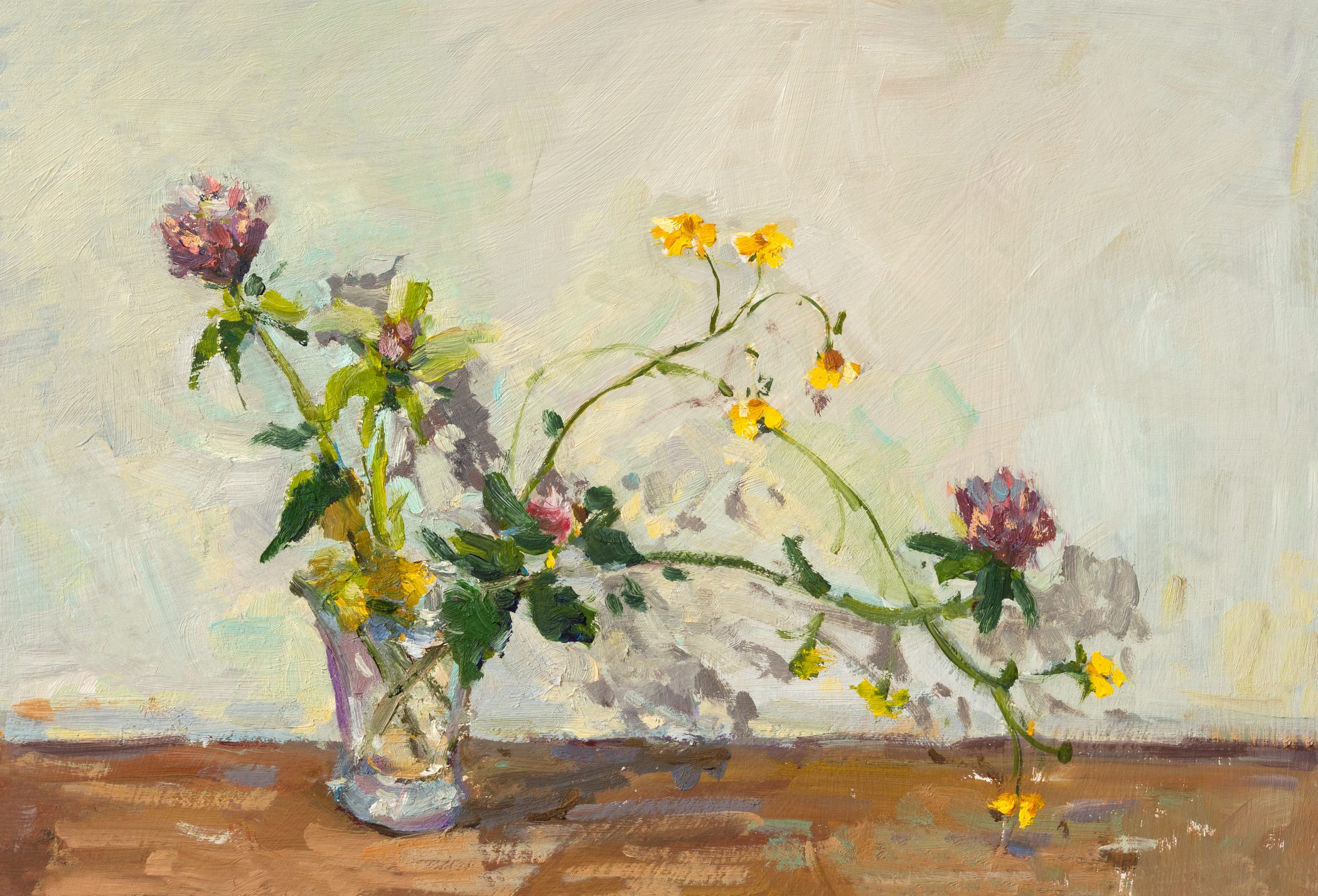 A delicate floral arrangement with yellow and purple flowers in a glass vase.