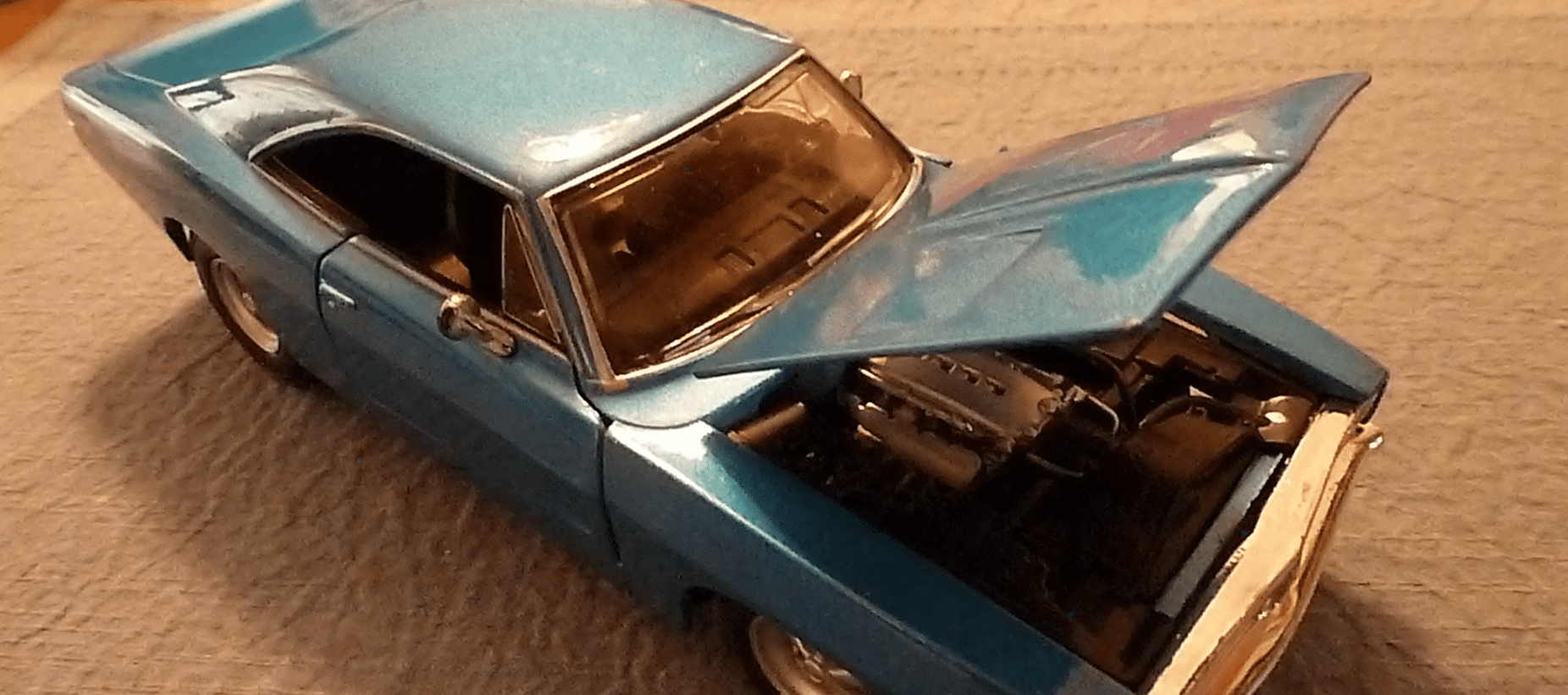 A blue car with its hood open showing the engine.