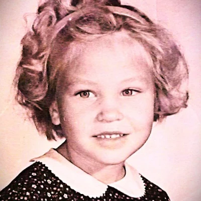 Black and white portrait of a young girl with curly hair and a collared dress.