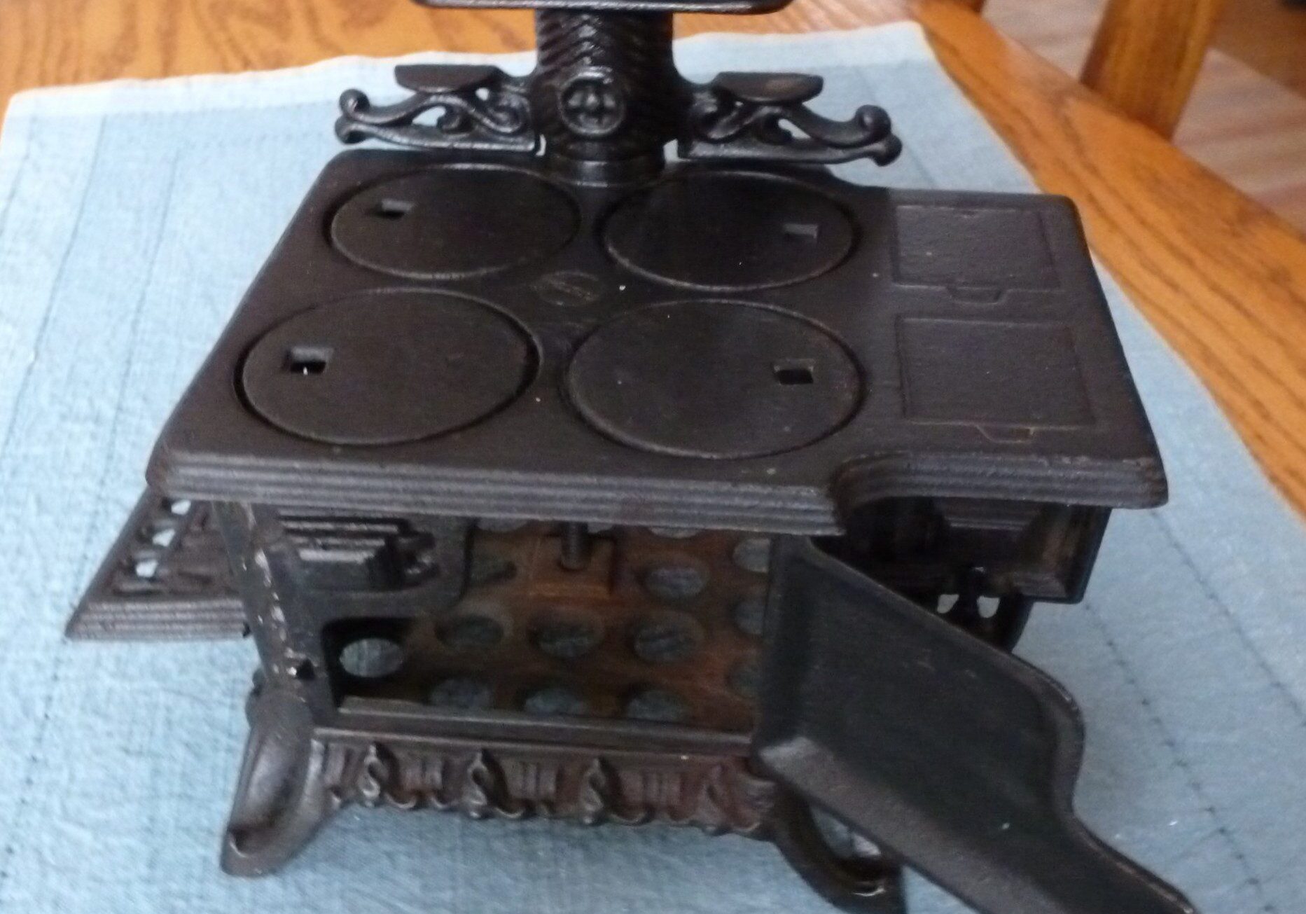 Antique black cast iron stove with open oven door, showcasing intricate design and craftsmanship.